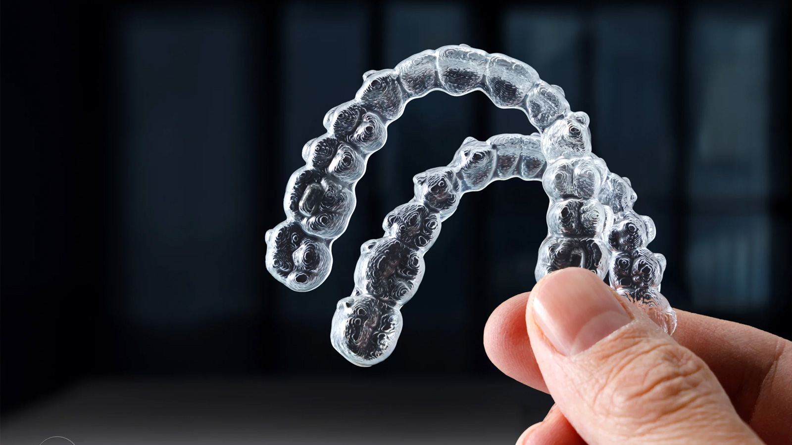 Invisalign aligners held between fingers