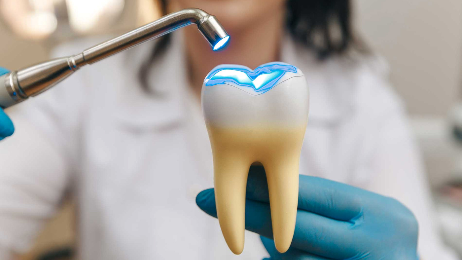 Процесс использования стоматологической полимеризационной лампы для отверждения композитного материала (пломбы или герметика) на модели зуба