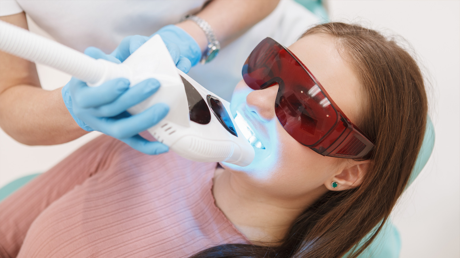 Пациентка, которой профессиональный стоматолог проводит отбеливание зубов